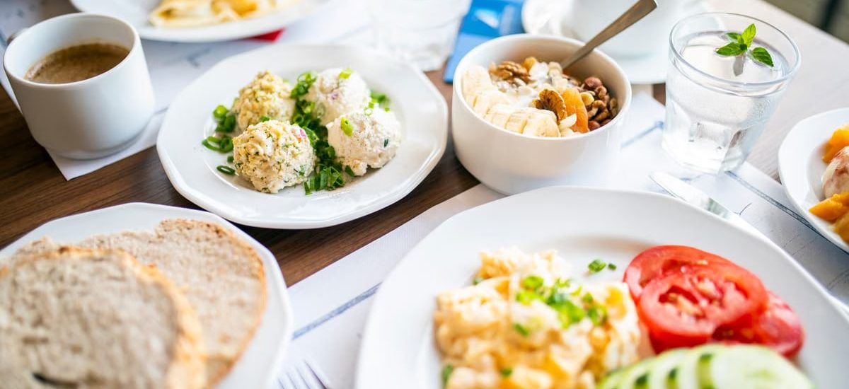 From above of tasty brunch of power bowl and scrambled eggs with fresh vegetable slices against drinks on table