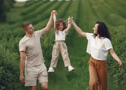 Joyful family moment in a green field during summer, capturing love and playfulness.
